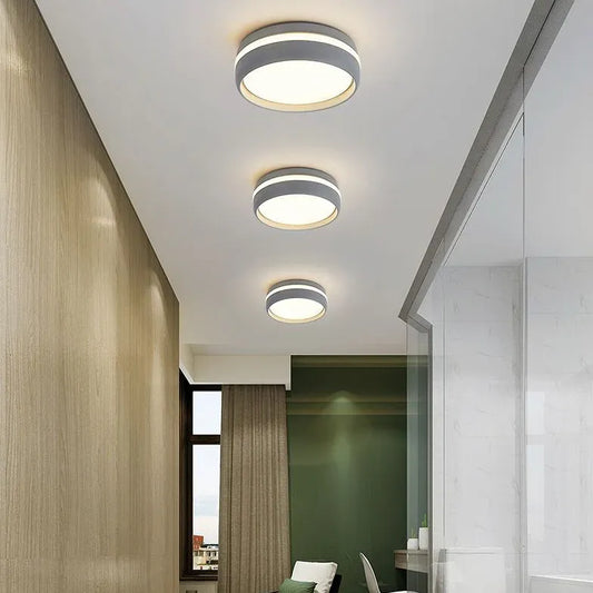 Moderne runde LED-Deckenleuchten in einem Flur mit weißer Decke und Holzverkleidung an der Wand, minimalistisches und funktionales Design.